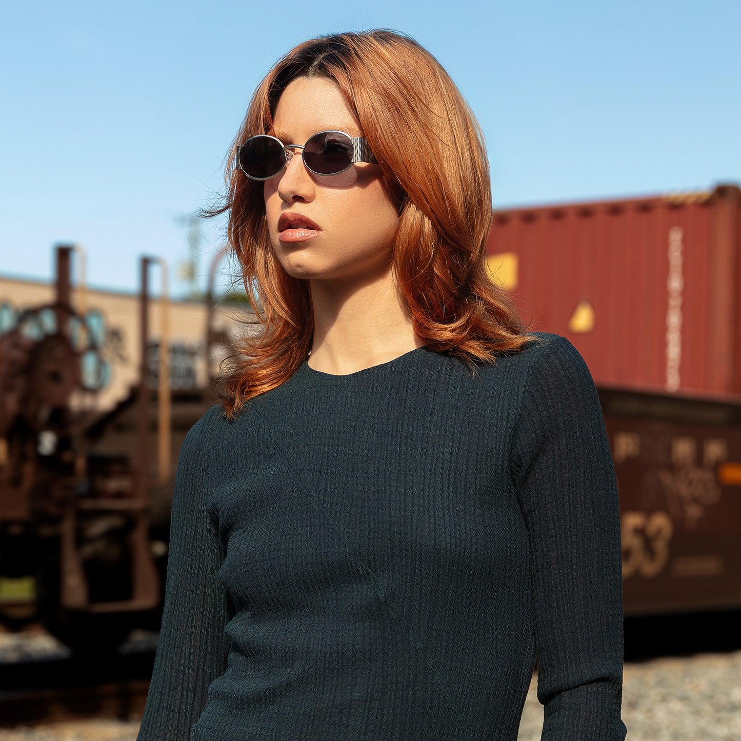 Model wearing Belle Meade Sunglasses in Silver Havana near train tracks