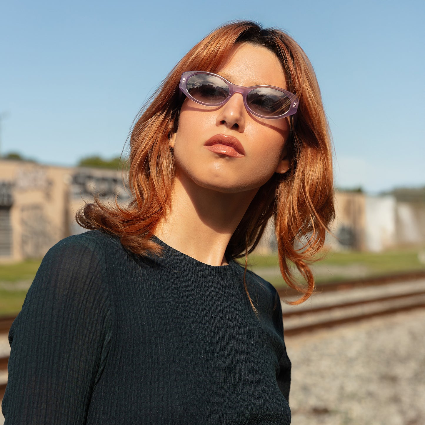 Model wearing Exumas Sunglasses in Lavender outdoor near train tracks
